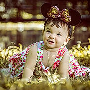 Roxan Paola is registered to the contest to win money with this photo: baby, child, infant, flowered_dress, headband, minnie_mouse_ears, grass, outdoor, sunlight, smiling, happy, crawling, nature, portrait, cute, accessory, jewelry, earrings, golden_light, bokeh