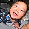 baby, smiling, superman, onesie, child, happy, portrait, indoors, blanket, stuffed_animal, face, cute, infant, closeup, person, lying_down, sleepwear, bright_eyes, skin, hand