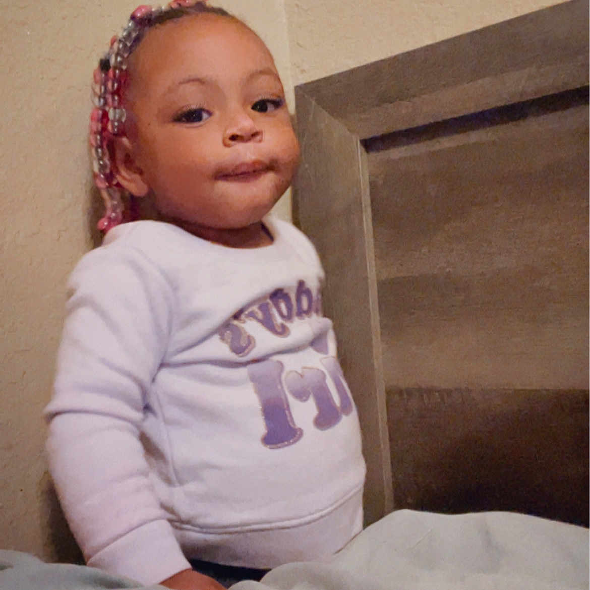 Dommoni is registered to the contest to win money with this photo: accessories, baby, bed, bodypart, closet, clothing, cupboard, earring, face, furniture, happy, head, indoors, jewelry, person, photography, portrait, sitting, smile, t_shirt