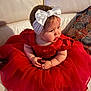 Aëlys participe au concours pour gagner de l'argent avec cette photo : baby, toddler, child, red_dress, headband, white_bow, sofa, couch, pillow, patterned_pillow, sitting, portrait, indoor, cute, chubby_cheeks, hands, toes, gaze, fabric, soft_lighting