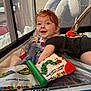Iris is registered to the contest to win money with this photo: baby, red_hair, smiling, playpen, toy, colorful, infant, happy, mesh, soft_lighting, child, indoor, play_mat, crawling, cute, person, face, curious, black_clothing, early_childhood