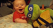 Memphis joined the competition — help win amazing prizes! baby, child, smiling, happy, plush_toy, teenage_mutant_ninja_turtle, pillow, bedroom, indoor, cuddling, red_shirt, foot, cozy, furniture, soft_toy, portrait, infant, cute, toy, home