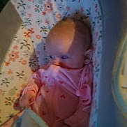 Emma joined the competition — help win amazing prizes! baby, infant, newborn, bassinet, crib, bedding, floral_pattern, onesie, pink_clothing, face, head, hand, blanket, mattress, indoors, portrait, blurry, low_light, shadow, sleepy