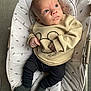 Elliot is registered to the contest to win money with this photo: baby, infant, child, mickey_mouse, sweater, black_pants, gray_socks, baby_rocker, leaf_pattern, carpet, indoor, portrait, small_hands, cute, looking_away, seated, young_child, cozy, casual_clothing, resting