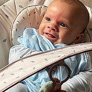 Elliot is registered to the contest to win money with this photo: baby, baby_seat, blue_blanket, child, closeup, clothing, comfort, cushion, cute, expression, face, happy, indoor, infant, person, play, smiling, soft_lighting, toy, young_child