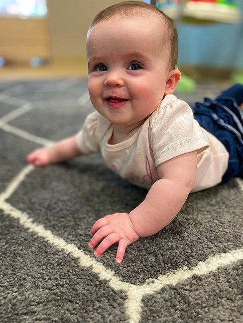 Juliana is registered to the contest to win money with this photo: asphalt, baby, baby_toddler_clothing, crawling, dress, face, facial_expression, finger, floor, flooring, grass, hand, happy, head, joy, leg, person, photograph, road_surface, smile