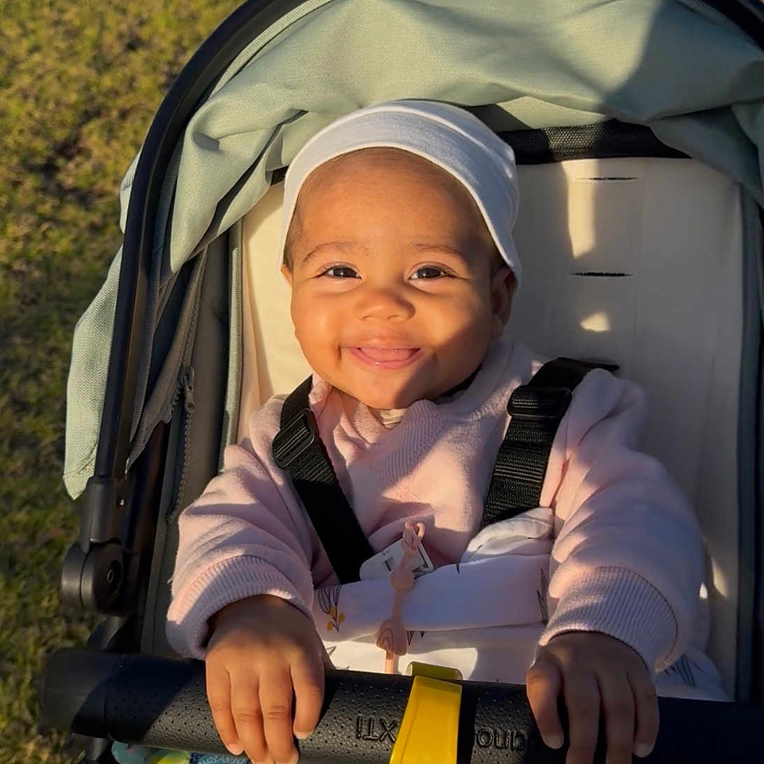 Aurohmie is registered to the contest to win money with this photo: baby, blanket, child, daytime, face, grass, hands, happy, hat, infant, outdoor, pacifier, park, pathway, seatbelt, smiling, stroller, sunlight, sweater, toy