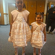 Taleah joined the competition — help win amazing prizes! two_girls, children, matching_dresses, pink_dresses, fuzzy_bolero, indoor, carpeted_floor, wooden_doors, smiling, hairstyles, shiny_shoes, young_children, holding_hands, portrait, people, girls, fashion, cute, happy, family_event