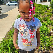 Taleah is registered to the contest to win money with this photo: child, girl, braids, beads, tshirt, mickey_mouse, minnie_mouse, outdoor, sidewalk, greenery, plants, sunlight, parking_lot, casual_clothing, smile, standing, daytime, young_child, cute, portrait