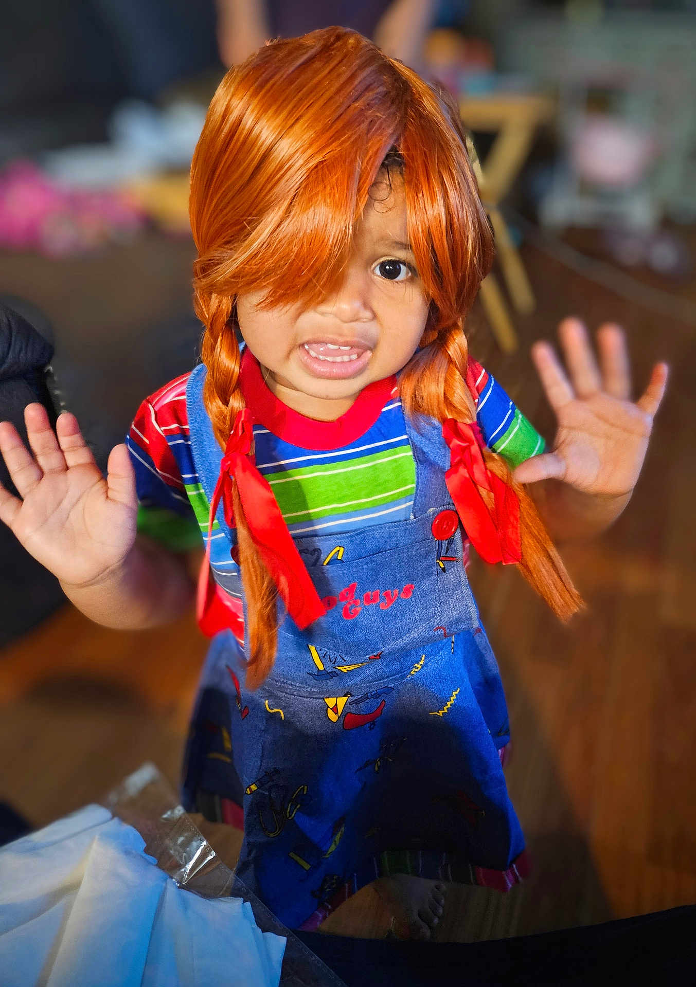 Tiani is registered to the contest to win money with this photo: blurry_background, child, colorful_clothing, expression, feet, hands_up, home, indoor, orange_hair, overalls, person, pigtails, playful, portrait, red_ribbons, smiling, striped_shirt, wig, wooden_floor, young_child