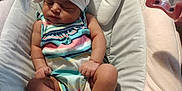 Tiani is registered to the contest to win money with this photo: baby, baby_seat, carpet, child, colorful_clothing, cushion, cute, headband, indoor, infant, peaceful, pink, relaxed, resting, sleeping, small, star_shaped_toy, striped_dress, toy, white