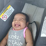 Tiani is registered to the contest to win money with this photo: baby, car_seat, child, chubby_cheeks, clothing, cute, face, happy, head, indoor, infant, infant_girl, pink_trim, portrait, safety_label, seat, sitting, smiling, text_on_clothing, young_child