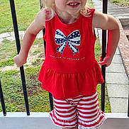 Brynnlee joined the competition — help win amazing prizes! child, blonde_hair, red_clothing, striped_shorts, outdoor, smiling, porch, railing, grass, trees, daylight, shoes, socks, cute, happy, person, young_child, casual, summer, playful