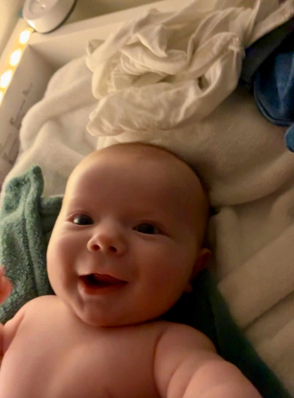 Léon a rejoint le concours — aidez-le/la à gagner de superbes lots ! baby, infant, smile, smiling, face, head, eyes, mouth, cheeks, skin, blanket, towel, bedding, indoors, portrait, close_up, newborn, cozy, soft_lighting, bare_shoulders