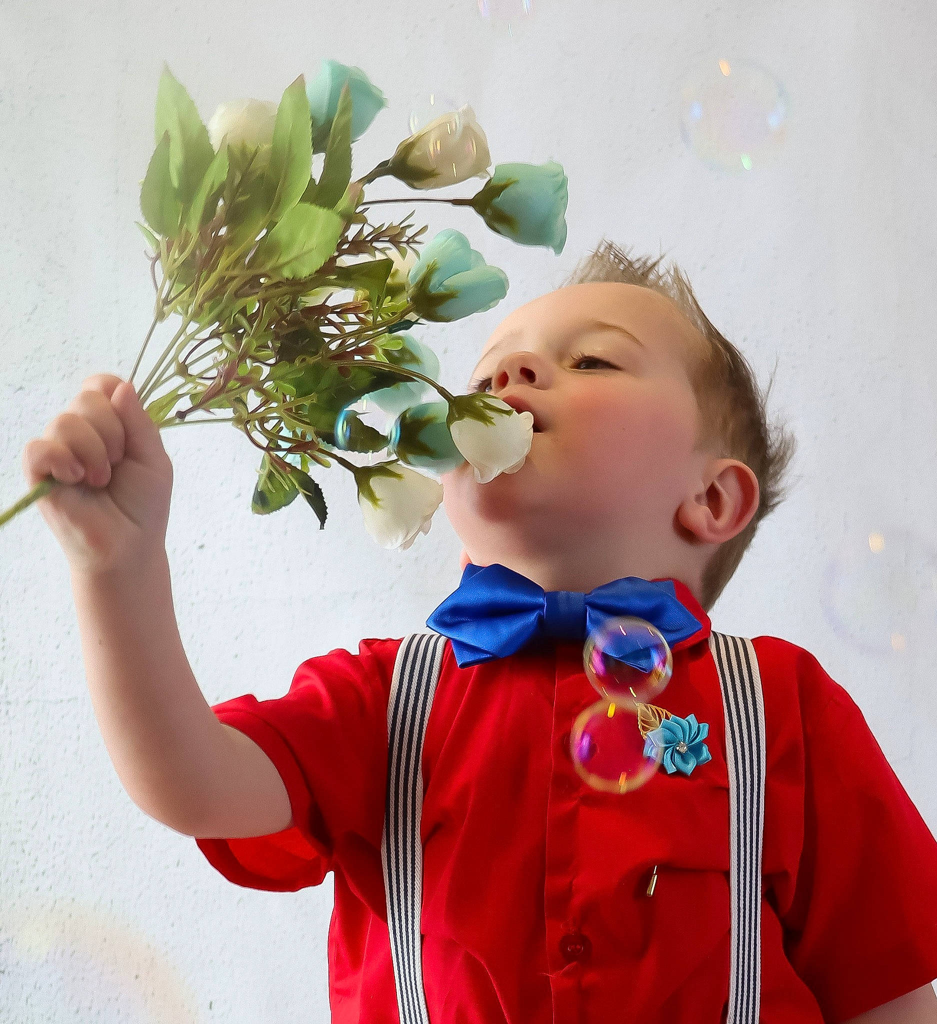 Aidan is registered to the contest to win money with this photo: artificial_flower, baby_toddler_clothing, bouquet, child, cut_flowers, electric_blue, facial_expression, fashion_accessory, floral_design, flower, flower_arranging, flowering_plant, gesture, hand, happy, person, plant, sleeve, standing, t_shirt