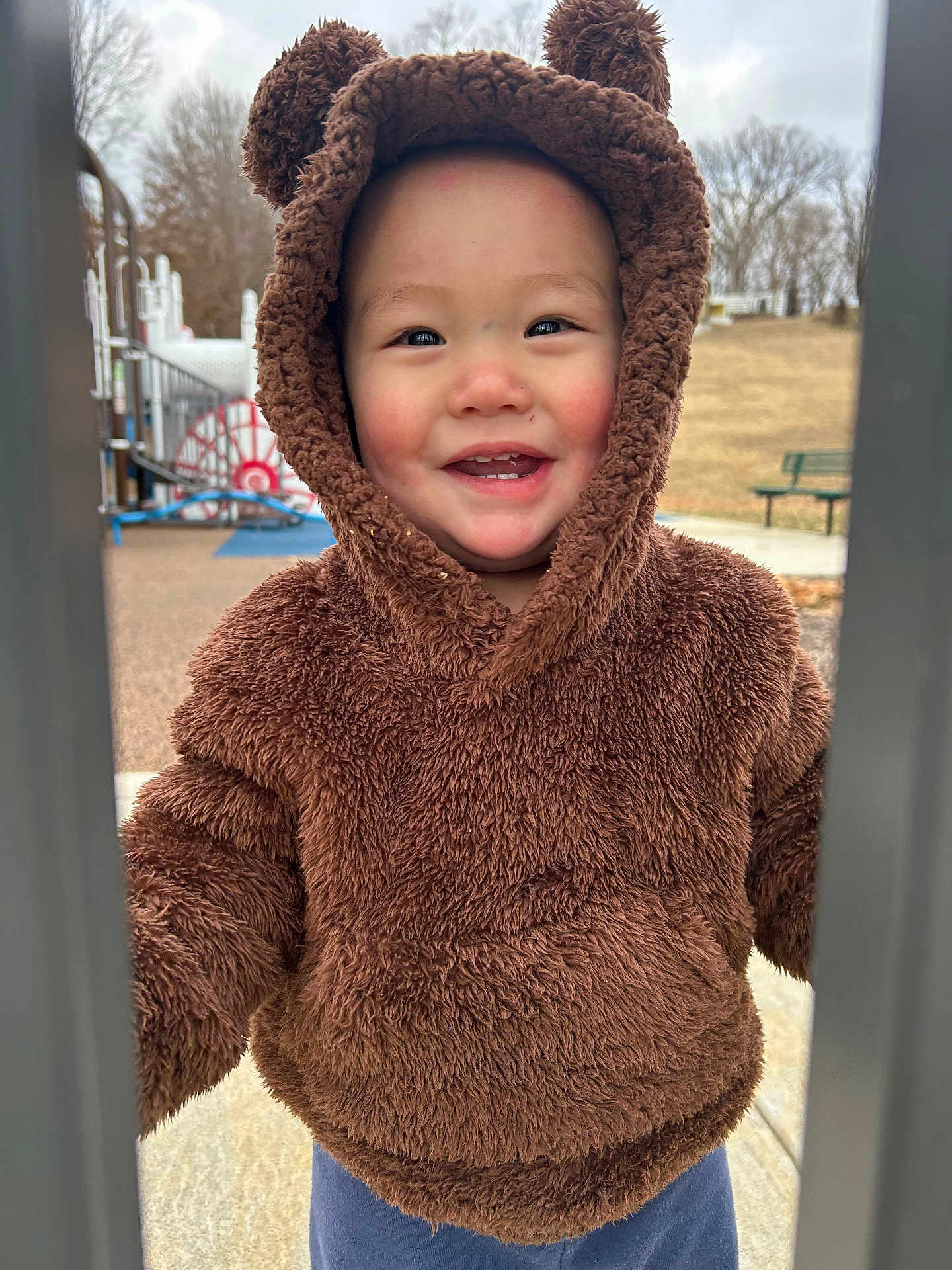 Koa is registered to the contest to win money with this photo: bench, cap, clothing, coat, face, furniture, happy, hat, head, hood, hoodie, jacket, knitwear, outdoors, person, photography, portrait, smile, sweater, sweatshirt
