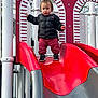 Koa is registered to the contest to win money with this photo: baby, clothing, coat, face, footwear, grass, head, jacket, nature, outdoorplayarea, outdoors, pants, person, photography, playarea, portrait, shoe, slide, sliding, toy