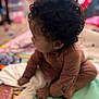 baby, blanket, child, clothing, colorful, cozy, curly_hair, cute, face, floor, hands, head, indoor, infant, person, play_area, portrait, sitting, soft_focus, young_child