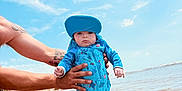 Roczen joined the competition — help win amazing prizes! baby, child, beach, water, sun_hat, swimsuit, tattoo, person, sky, sand, ocean, summer, outdoor, holding, shore, waves, blue, cute, infant, holiday