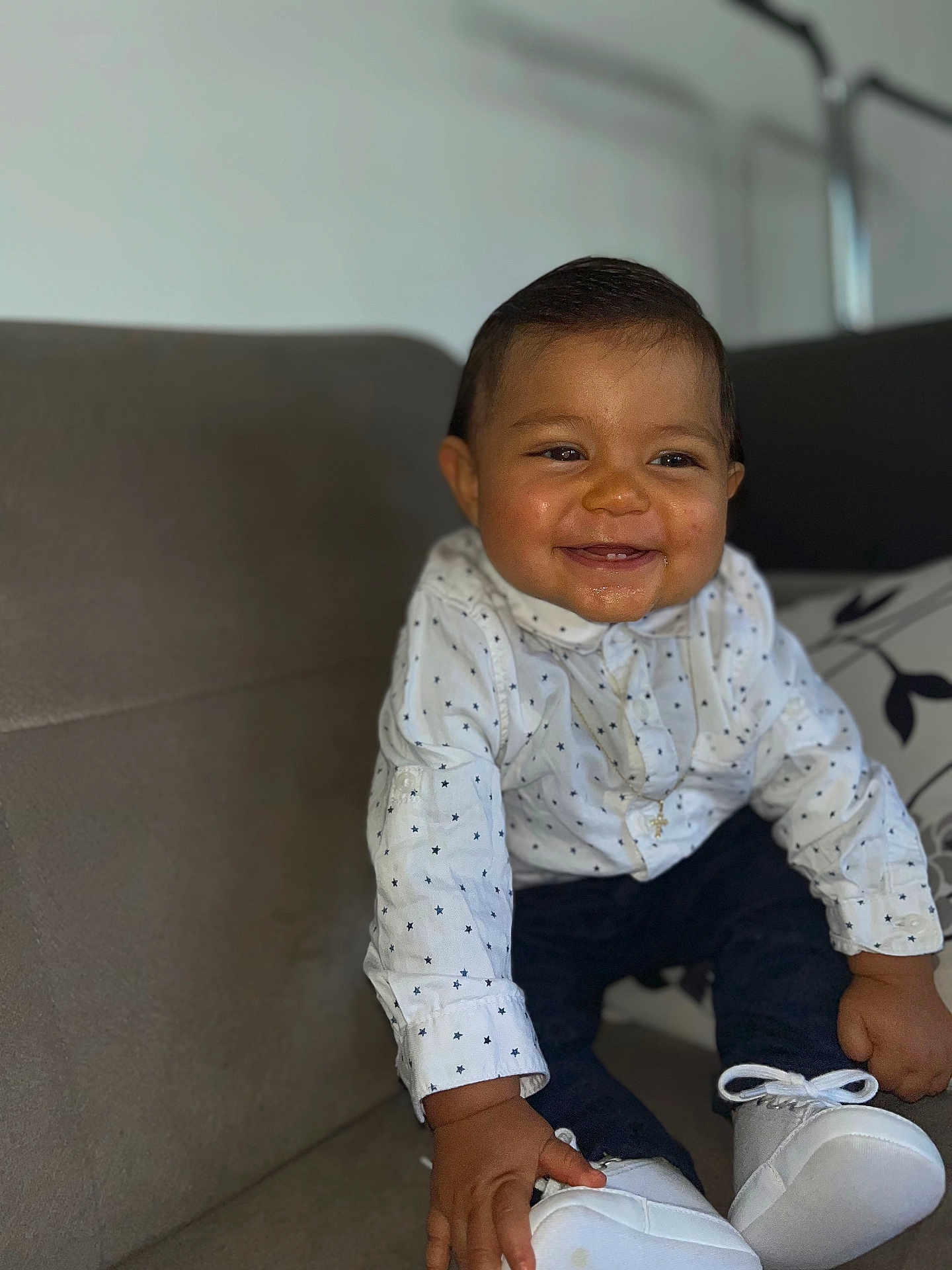 Kayden participe au concours pour gagner de l'argent avec cette photo : baby, child, smile, happy, shirt, star_pattern, pants, white_shoes, couch, indoor, portrait, cute, infant, clothing, sitting, hand, face, person, young, home
