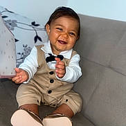 Kayden participe au concours pour gagner de l'argent avec cette photo : baby, child, smiling, sitting, couch, clothing, bow_tie, shoes, face, happy, indoor, cute, hands, portrait, one_person, infant, furniture, young_child, fashion, home