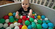 Anthony joined the competition — help win amazing prizes! baby, baby_toys, ball_pit, black_shirt, child, colorful_balls, crib, cute, flooring, furniture, home, indoor, infant, nursery, person, play_area, playtime, smiling, toys, young_child