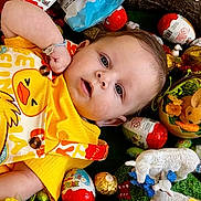 Owen participe au concours pour gagner de l'argent avec cette photo : baby, child, yellow_clothing, duck_print, toy_animals, easter_eggs, kinder_surprise, lying_down, blue_eyes, bracelet, colorful, cute, indoor, playful, holiday, spring, flowers, green_background, small_toys, infant