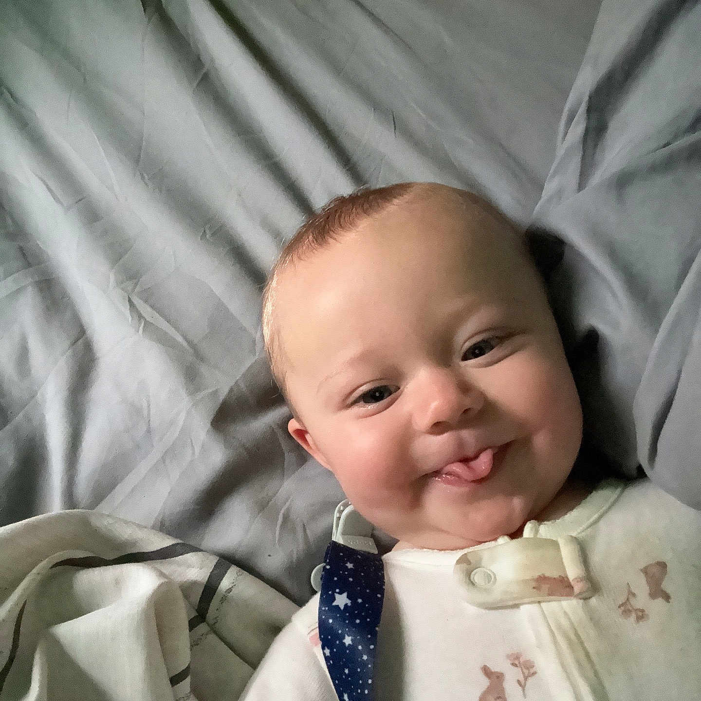Arizona is registered to the contest to win money with this photo: baby, bed, bedding, blanket, child, cute, expression, face, head, home, indoors, infant, pajamas, person, playful, skin, sleep, sleepwear, smiling, tongue