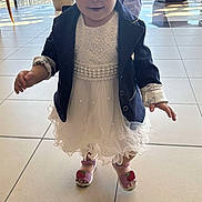 Mia a rejoint le concours — aidez-le/la à gagner de superbes lots ! toddler, child, indoor, dress, white_dress, blazer, navy_blazer, sandals, pink_sandals, strawberry, curly_hair, walking, floor_tiles, sunlight, window, portrait, cute, fashion, person, young_child