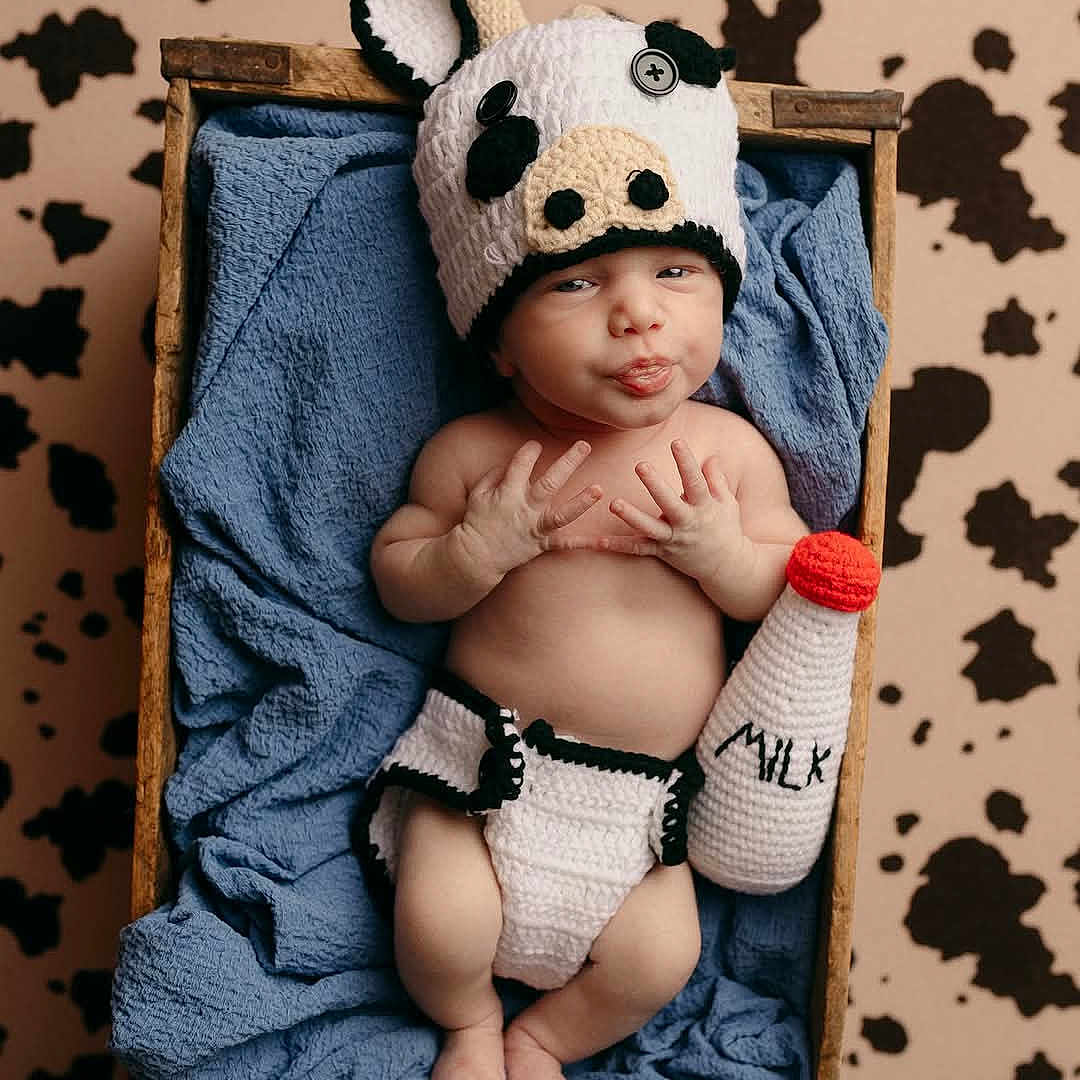 Kody joined the competition — help win amazing prizes! baby, blue_blanket, button_eyes, child, cow_print_background, crocheted_diaper_cover, crocheted_hat, cute, expression, hand_gesture, indoors, infant, knitted, lying_down, milk_bottle, newborn, playful, portrait, soft_texture, wooden_crate