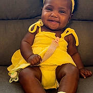 Harmony is registered to the contest to win money with this photo: baby, child, smiling, yellow_dress, headband, pacifier, socks, sitting, couch, indoor, cute, happy, infant, portrait, person, face, skin, clothing, accessory, comfort