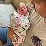 Roy joined the competition — help win amazing prizes! newborn, baby, infant, swaddled, blanket, footprints, person, adult, man, shirt, fire_strong_emblem, holding, cradling, hospital, bed, phone, blue_shorts, skin, face, closed_eyes