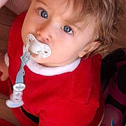 Lowenn a rejoint le concours — aidez-le/la à gagner de superbes lots ! baby, blue_eyes, cardboard, child, closeup, curly_hair, cute, festive, floor, hand, indoor, looking_up, pacifier, person, red_clothing, sitting, sock, toddler, watch, wooden_floor