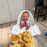 Weston joined the competition — help win amazing prizes! baby, chair, child, clothing, cute, dog, door, flooring, food, hand, happy, high_chair, indoor, kitchen, mini_waffles, person, plate, smiling, table, wood_floor