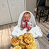 baby, chair, child, clothing, cute, dog, door, flooring, food, hand, happy, high_chair, indoor, kitchen, mini_waffles, person, plate, smiling, table, wood_floor