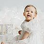 baby, child, white_dress, smiling, sitting, balloons, fairy_lights, reflection, portrait, happy, cute, celebration, indoors, soft_lighting, blond_hair, blue_eyes, infant, decor, elegant_clothing, festive