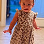 toddler, child, leopard_print, dress, barefoot, indoor, floor, walking, cute, young_child, person, portrait, smiling, curly_hair, home, baby, skin, face, arm, leg
