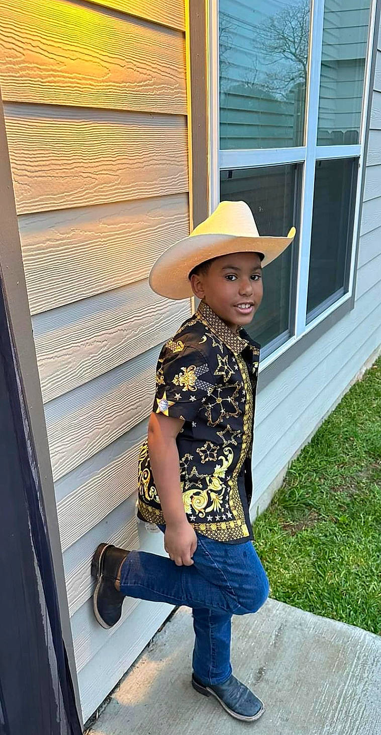 Bradley is registered to the contest to win money with this photo: cool, denim, electric_blue, fashion_accessory, fashion_design, fun, happy, hat, headgear, headwear, leisure, pattern, person, sleeve, smile, standing, sun_hat, t_shirt, waist, window