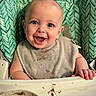 baby, high_chair, bib, messy, food, smiling, happy, face, child, meal, chocolate, green_background, feeding, cute, small_hand, indoor, portrait, infant, expression, table
