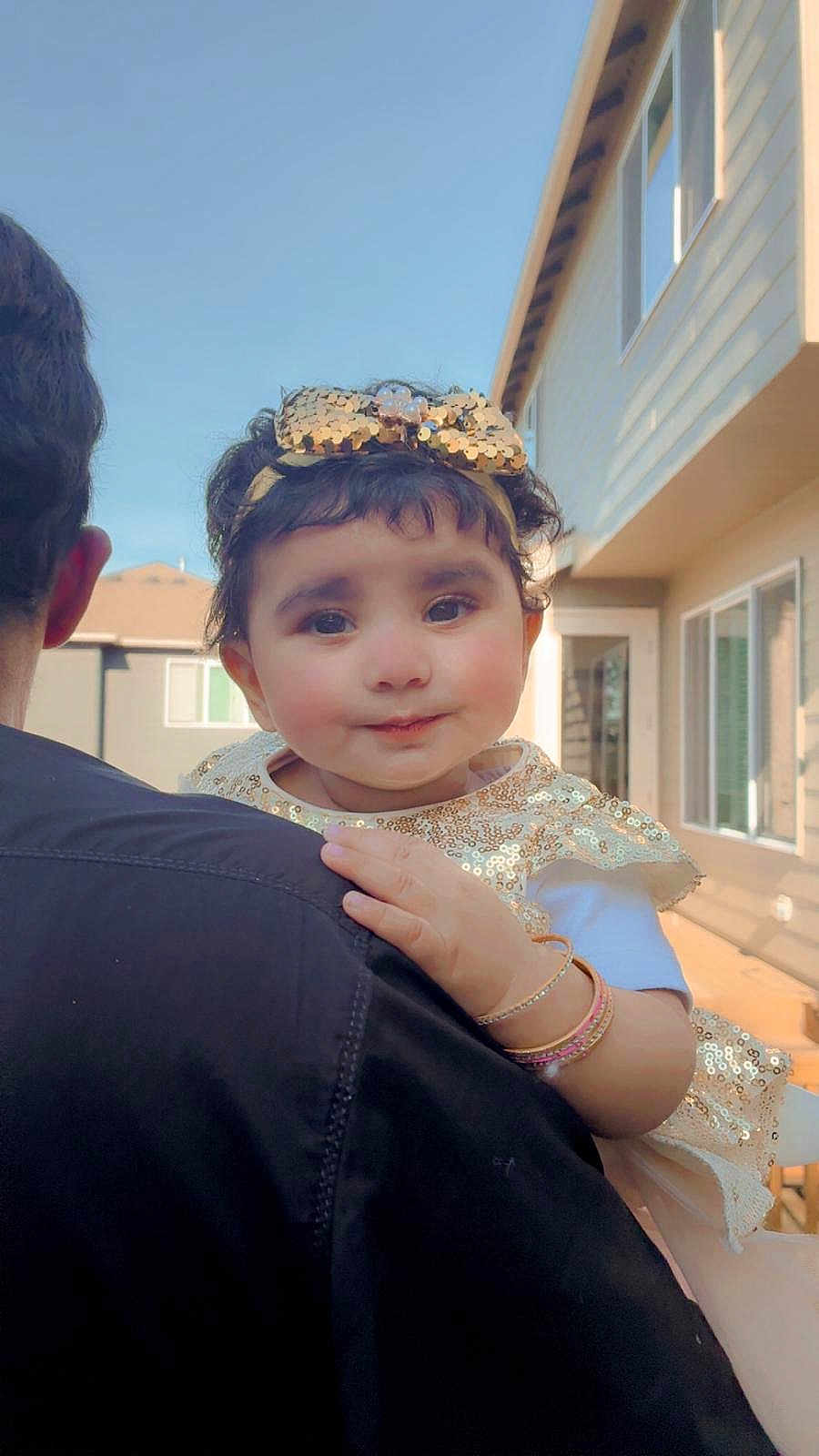 Hafsa Saad joined the competition — help win amazing prizes! toddler, child, smile, gold_bow, gold_dress, bracelets, adult, backyard, house, window, daylight, person, cute, portrait, holding, face, happy, outdoor, family, curly_hair