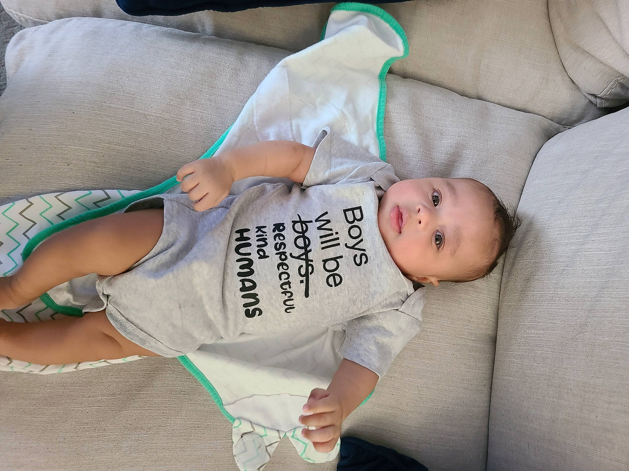 Dante is registered to the contest to win money with this photo: abdomen, baby, baby_products, baby_toddler_clothing, child, comfort, couch, elbow, finger, hand, human_leg, joint, knee, leg, linens, person, sitting, skin, sleeve, thigh