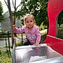 active, butterfly, casual_clothing, child, climbing, daylight, fence, fun, metal_slide, nature, outdoor, park, pink_sweater, playground, red_playground_equipment, slide, smiling_face, toddler, trees, young_child
