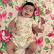 Jenevieve is registered to the contest to win money with this photo: baby, infant, child, smiling, lying_down, floral_pattern, blanket, onesie, hair_ties, cute, happy, skin, face, hands, legs, feet, indoors, soft_texture, colorful, comfort