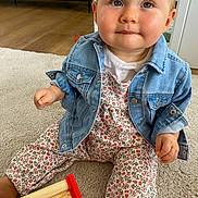 Sixtine a rejoint le concours — aidez-le/la à gagner de superbes lots ! baby, child, denim_jacket, floral_outfit, carpet, wooden_toy, indoor, cute, blue_eyes, curious, sitting, playful, adorable, infant, hands, face, expression, clothing, floor, person