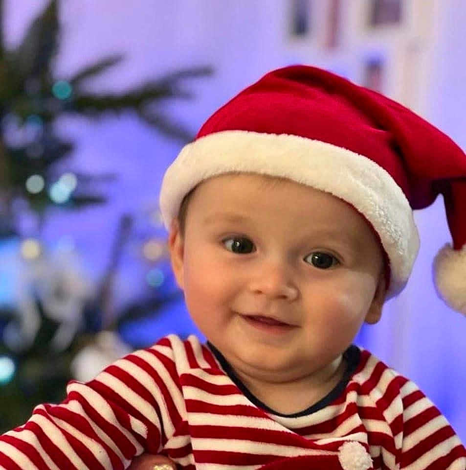 Nail a rejoint le concours — aidez-le/la à gagner de superbes lots ! baby, child, smiling, face, santa_hat, striped_clothing, holiday, christmas_tree, festive, indoors, portrait, cute, happy, person, headwear, red, white, blurred_background, celebration, seasonal