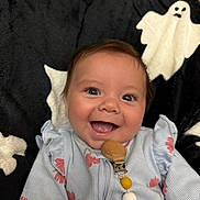 Abriela is registered to the contest to win money with this photo: baby, smiling, infant, pacifier_clip, blue_clothing, floral_pattern, blanket, ghost_pattern, happy, face, cute, child, indoors, closeup, young, person, portrait, comfort, soft_texture, clothing