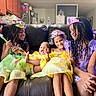 child, children, princess_dress, tiara, smiling, laughing, couch, indoor, family, playful, costume, braids, happy, girls, living_room, fun, sitting, colorful, joy, friends