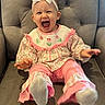 Ivy joined the competition — help win amazing prizes! baby, child, girl, smiling, laughing, bow, headband, pink_clothing, floral_pattern, sitting, armchair, gray_furniture, happy, cute, toddler, indoors, portrait, feet, sock, comfortable