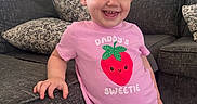 Ivy joined the competition — help win amazing prizes! toddler, child, smiling, pink_shirt, strawberry_graphic, text_on_clothing, couch, pillows, living_room, home_interior, happy, person, curtains, mirror, ceiling_fan, floor_tiles, hand, red_pants, portrait, casual