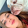 dog, bulldog, white_dog, woman, portrait, face, indoors, chair, close_up, pet, companion, wrinkles, sleepy, cuddling, long_hair, red_clothing, smartphone, casual, selfie, funny